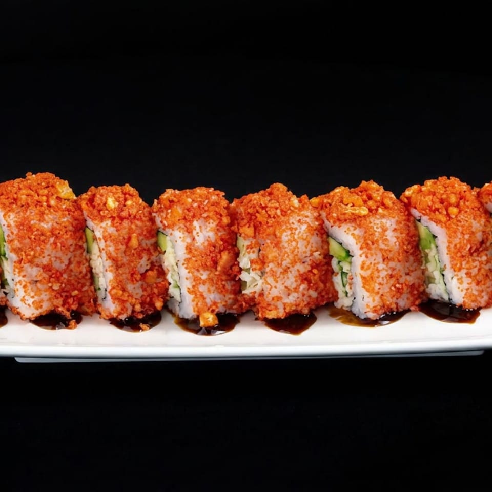 Sushi rolls coated in crunchy red topping, arranged on a white rectangular plate with sauce and vegetables against a black background.